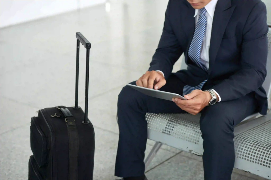 Persona in abito formale con valigia e tablet, simbolo dei servizi business dell’Hotel Tigullio a Rapallo