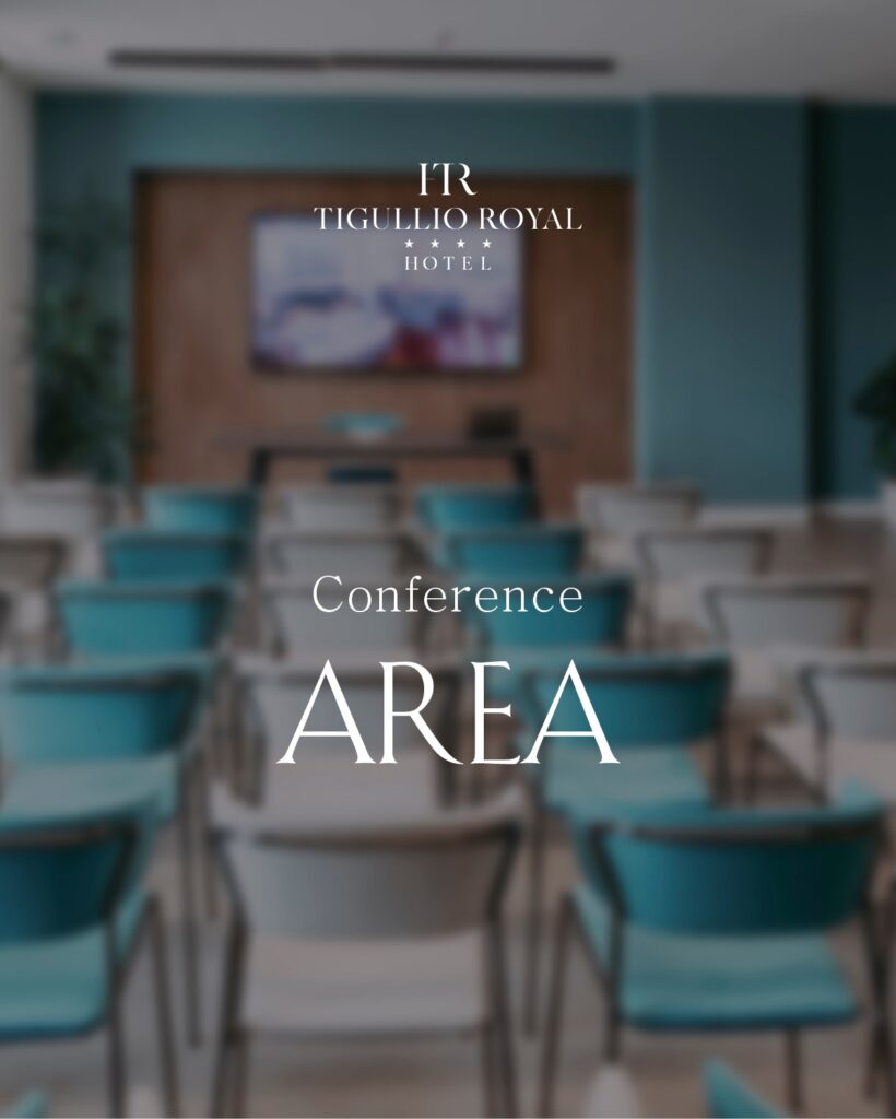 Sala conferenze del Tigullio Royal Hotel con file ordinate di sedie imbottite color turchese rivolte verso un tavolo frontale e uno schermo a parete; ambiente moderno e luminoso con scritta sovrimpressa “Conference Area" e logo dell'hotel